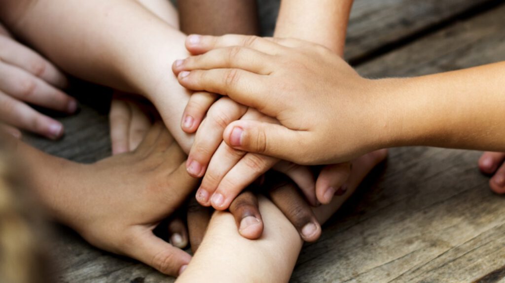 Hände aufeinandergelegt, Symbol für Gemeinschaft und Zusammenhalt